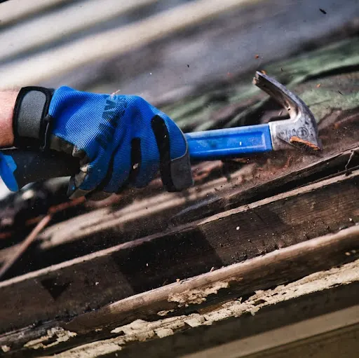 A worker uses a hammer to tear off a roof