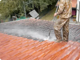 A roofer cleaning off a dirty roof.