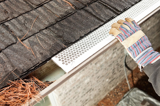 Installing gutter guard to keep gutters from clogging.