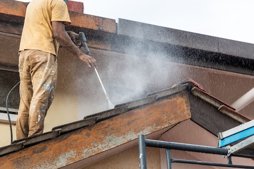 A roofer cleaning a roof during moss removal.