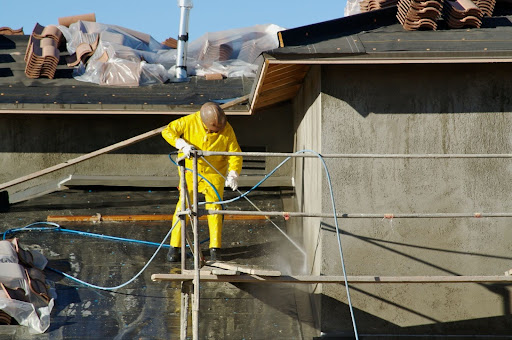 A roofer cleaning with a power washer.