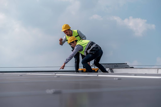 Two roofers cleaning a roof.